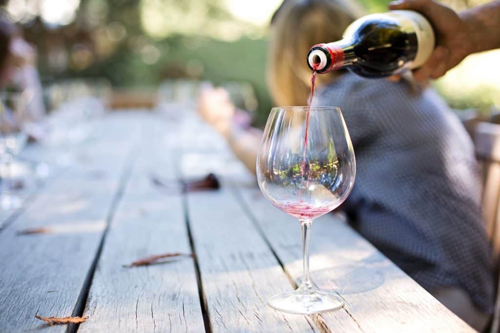 Pouring red wine into a glass outdoors.